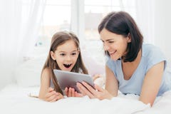 De mooie moeder en de dochter letten op iets die grappig op tabletcomputer, aan draadloos Internet wordt aangesloten, doorbrengen stock foto's De mooie moeder en de dochter letten op iets die grappig op tabletcomputer, aan draadloos Internet wordt aangesloten, doorbrengen stock foto's