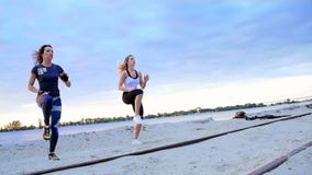 De mooie, slanke jonge vrouwen zijn bezig geweest met geschiktheid, sprong, uitvoeren sterkteoefeningen Bij dageraad, bij de zand stock footage De mooie, slanke jonge vrouwen zijn bezig geweest met geschiktheid, sprong, uitvoeren sterkteoefeningen Bij dageraad, bij de zand stock footage