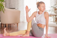 De mooie vrouw oefent yoga uit, doend Ardha Matsyendrasana stel thuis royalty-vrije stock fotografie De mooie vrouw oefent yoga uit, doend Ardha Matsyendrasana stel thuis royalty-vrije stock fotografie