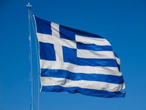 De nationale vlag van Griekenland op de vlaggestok ontwikkelt zich in de wind tegen de blauwe hemel stock afbeelding De nationale vlag van Griekenland op de vlaggestok ontwikkelt zich in de wind tegen de blauwe hemel stock afbeelding
