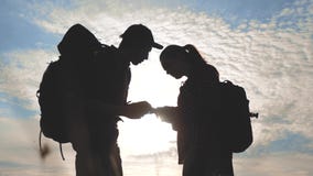 De navigatieconcept van het groepswerktoerisme Het gelukkige silhouet van familiewandelaars in aard die in een weg van de smartph stock video De navigatieconcept van het groepswerktoerisme Het gelukkige silhouet van familiewandelaars in aard die in een weg van de smartph stock video