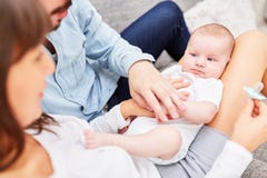 De ouders zitten ontspannen met hun kleine baby stock foto De ouders zitten ontspannen met hun kleine baby stock foto