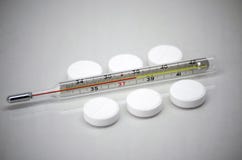 De pillen liggen naast de medische thermometer royalty-vrije stock afbeeldingen De pillen liggen naast de medische thermometer royalty-vrije stock afbeeldingen