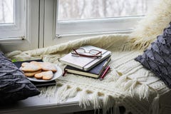 De plaid, hoofdkussens, boeken, koekjes ligt op het venster stock foto De plaid, hoofdkussens, boeken, koekjes ligt op het venster stock foto