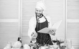 De recepten van de boekfamilie Volgens recept Kokende voedsel van de mensen het gebaarde chef-kok Kerel gelezen boekrecepten Culi stock fotografie De recepten van de boekfamilie Volgens recept Kokende voedsel van de mensen het gebaarde chef-kok Kerel gelezen boekrecepten Culi stock fotografie