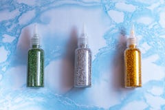 De reeks van smaragd, zilver en goud schittert in plastic flessen voor zeep het maken op de oppervlakte van blauw marmer, omhoog royalty-vrije stock fotografie De reeks van smaragd, zilver en goud schittert in plastic flessen voor zeep het maken op de oppervlakte van blauw marmer, omhoog royalty-vrije stock fotografie