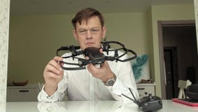 De rijpe mens met glazen en een wit overhemd verzamelt een quadrocopter, onderzoekt het, het concept het bestuderen van technolog stock videobeelden De rijpe mens met glazen en een wit overhemd verzamelt een quadrocopter, onderzoekt het, het concept het bestuderen van technolog stock videobeelden