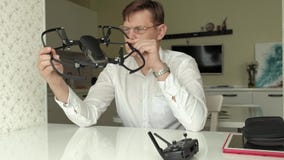 De rijpe mens met glazen en een wit overhemd verzamelt een quadrocopter, onderzoekt het, het concept het bestuderen van technolog stock video De rijpe mens met glazen en een wit overhemd verzamelt een quadrocopter, onderzoekt het, het concept het bestuderen van technolog stock video