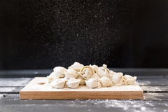 de ruwe bollen op een scherpe Raad op een donkere achtergrond, bloem giet op de bollen op bovenkant stock fotografie de ruwe bollen op een scherpe Raad op een donkere achtergrond, bloem giet op de bollen op bovenkant stock fotografie