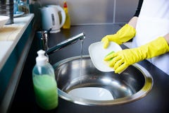 De schotels van de vrouwenwas in de keuken met spons stock fotografie De schotels van de vrouwenwas in de keuken met spons stock fotografie