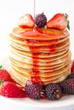 De smakelijke ontbijtpannekoeken met fruit, aardbeien en braambessenmora worden gegoten met de jam van de aardbeistroop Close-up royalty-vrije stock afbeelding De smakelijke ontbijtpannekoeken met fruit, aardbeien en braambessenmora worden gegoten met de jam van de aardbeistroop Close-up royalty-vrije stock afbeelding