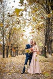 De Smilngjonggehuwden koesteren onder een val van de herfstbladeren royalty-vrije stock afbeelding De Smilngjonggehuwden koesteren onder een val van de herfstbladeren royalty-vrije stock afbeelding