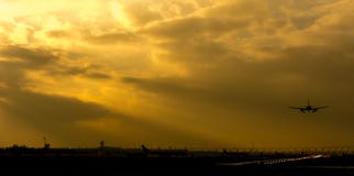 De sombere landende vliegtuigen van het luchthavenlandschap met zon die door wolken glanzen royalty-vrije stock foto De sombere landende vliegtuigen van het luchthavenlandschap met zon die door wolken glanzen royalty-vrije stock foto