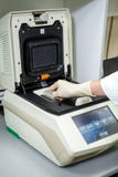 De specialist van het laboratorium plaatst de steekproeven in een speciaal apparaat om de samenstelling te bestuderen royalty-vrije stock afbeelding De specialist van het laboratorium plaatst de steekproeven in een speciaal apparaat om de samenstelling te bestuderen royalty-vrije stock afbeelding