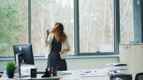 De speelse jonge dame danst in bureau die haar haar werpen en pret hebben en glazen opstijgen die dan lopend lachen stock video De speelse jonge dame danst in bureau die haar haar werpen en pret hebben en glazen opstijgen die dan lopend lachen stock video