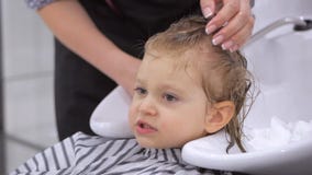 De stilistkapper wast het hoofd van een leuke meisjezitting als voorzitter in een schoonheidssalon Het kappen, hoofd stock videobeelden De stilistkapper wast het hoofd van een leuke meisjezitting als voorzitter in een schoonheidssalon Het kappen, hoofd stock videobeelden