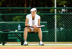 De succesvolle vrouwelijke rust van de tennisspeler bij de bank royalty-vrije stock foto's De succesvolle vrouwelijke rust van de tennisspeler bij de bank royalty-vrije stock foto's