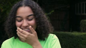 De tiener jonge vrouw van het Biracial Afrikaanse Amerikaanse meisje buiten het gebruiken van haar slimme celtelefoon voor social stock footage De tiener jonge vrouw van het Biracial Afrikaanse Amerikaanse meisje buiten het gebruiken van haar slimme celtelefoon voor social stock footage