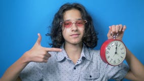 De tijd is geld de grappige tiener in roze glazen houdt een klok in haar handen en toont haar vingers het geldteken stock videobeelden De tijd is geld de grappige tiener in roze glazen houdt een klok in haar handen en toont haar vingers het geldteken stock videobeelden