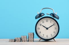 De tijd is Geldconcept, stapelend muntstukken en wekker op houten stock foto De tijd is Geldconcept, stapelend muntstukken en wekker op houten stock foto