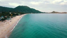 De toeristenmensen die op overzees strand op achtergrondpalm en heuvelantenne rusten bekijken stock footage De toeristenmensen die op overzees strand op achtergrondpalm en heuvelantenne rusten bekijken stock footage