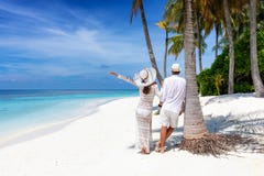 De tribunes van het reizigerspaar op een mooi, tropisch strand royalty-vrije stock fotografie De tribunes van het reizigerspaar op een mooi, tropisch strand royalty-vrije stock fotografie