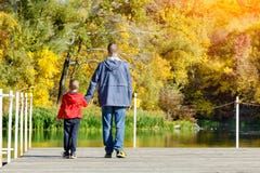 De vader en de zoon lopen langs de pijler De zonnige herfst, achterv royalty-vrije stock afbeelding De vader en de zoon lopen langs de pijler De zonnige herfst, achterv royalty-vrije stock afbeelding