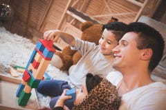 De vader, de zoon en weinig babydochter spelen thuis met kubussen voor kinderen bij nacht stock fotografie De vader, de zoon en weinig babydochter spelen thuis met kubussen voor kinderen bij nacht stock fotografie