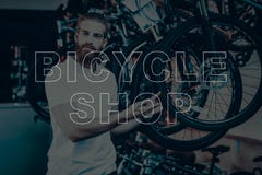 De verkoper in een fietswinkel stelt dichtbij een fiets stock foto's De verkoper in een fietswinkel stelt dichtbij een fiets stock foto's
