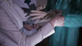 De verpleegster helpt de arts om op witte medische handschoenen te zetten stock video De verpleegster helpt de arts om op witte medische handschoenen te zetten stock video