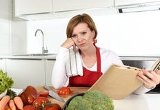De verstoorde kokvrouw bored en frustreerde het boek van lezingsrecepten in huiskeuken in spanning stock foto De verstoorde kokvrouw bored en frustreerde het boek van lezingsrecepten in huiskeuken in spanning stock foto