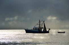 De visserij van treilerboot in haven stormachtige zonsondergang royalty-vrije stock foto De visserij van treilerboot in haven stormachtige zonsondergang royalty-vrije stock foto