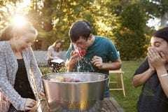 De vrienden letten tienerappel op het bobbing bij tuinpartij stock foto De vrienden letten tienerappel op het bobbing bij tuinpartij stock foto