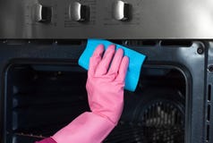De vrouw dient beschermende handschoen thuis in met vodden schoonmakende oven ki royalty-vrije stock afbeelding De vrouw dient beschermende handschoen thuis in met vodden schoonmakende oven ki royalty-vrije stock afbeelding
