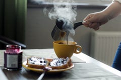 De vrouw giet hete koffie van cezve in mok royalty-vrije stock afbeeldingen De vrouw giet hete koffie van cezve in mok royalty-vrije stock afbeeldingen
