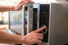 De vrouw ` s geeft af Sluitende Microgolf Oven Door And Preparing Food stock afbeelding De vrouw ` s geeft af Sluitende Microgolf Oven Door And Preparing Food stock afbeelding