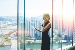 De vrouwelijke econoom bevindt zich dichtbij bureauvenster met mening van ontwikkeld bedrijfsdistrict in China royalty-vrije stock foto De vrouwelijke econoom bevindt zich dichtbij bureauvenster met mening van ontwikkeld bedrijfsdistrict in China royalty-vrije stock foto