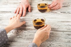 De vrouwelijke en mannelijke handen worden gehouden op de lijst Handen en thee op weefsel achtergrondexemplaarruimte en close-up stock foto De vrouwelijke en mannelijke handen worden gehouden op de lijst Handen en thee op weefsel achtergrondexemplaarruimte en close-up stock foto