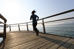 De vrouwelijke oefening van de joggerochtend op kustpromenade tijdens zonsopgang Stock Fotografie De vrouwelijke oefening van de joggerochtend op kustpromenade tijdens zonsopgang Stock Fotografie