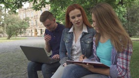 De vrouwelijke student schrijft in haar oefenboek op campus royalty-vrije stock foto De vrouwelijke student schrijft in haar oefenboek op campus royalty-vrije stock foto