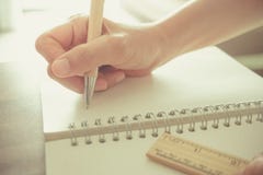 De vrouwenhand schrijft op wit notitieboekje stock foto De vrouwenhand schrijft op wit notitieboekje stock foto
