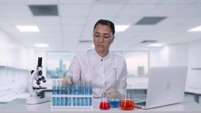 De vrouwenmicrobioloog analyseert de vloeistof in een de gedragingen van de reageerbuisa vrouwelijk wetenschapper medisch onderzo stock video De vrouwenmicrobioloog analyseert de vloeistof in een de gedragingen van de reageerbuisa vrouwelijk wetenschapper medisch onderzo stock video
