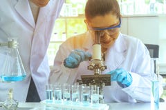 De wetenschappers verklaren experimenten door de microscoop in het laboratorium af te tasten Wetenschappers die in laboratorium w royalty-vrije stock foto De wetenschappers verklaren experimenten door de microscoop in het laboratorium af te tasten Wetenschappers die in laboratorium w royalty-vrije stock foto