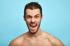 De woedende shirtless mens toont negatieve die emoties, gevoel, over blauwe achtergrond wordt geïsoleerd stock afbeeldingen De woedende shirtless mens toont negatieve die emoties, gevoel, over blauwe achtergrond wordt geïsoleerd stock afbeeldingen