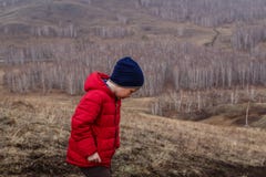 De zes-jaar-oude jongen in een rood jasje loopt buiten de stad in de lente in de hooglanden royalty-vrije stock fotografie De zes-jaar-oude jongen in een rood jasje loopt buiten de stad in de lente in de hooglanden royalty-vrije stock fotografie
