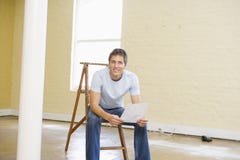 De zitting van de mens op ladder in een lege ruimte met document royalty-vrije stock foto De zitting van de mens op ladder in een lege ruimte met document royalty-vrije stock foto