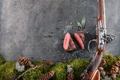 Deer or venison steak with antique long gun and ingredients like sea salt, herbs and pepper, food background for restaurant or hun stock photos Deer or venison steak with antique long gun and ingredients like sea salt, herbs and pepper, food background for restaurant or hun stock photos