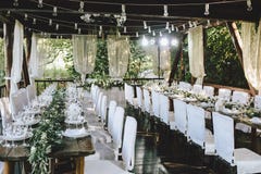 Dekorujący elegancki drewniany ślubu stół dla bankieta plenerowego w ogrodowym gazebo z lampą, w stylu wieśniaka z eukaliptusem i obrazy stock Dekorujący elegancki drewniany ślubu stół dla bankieta plenerowego w ogrodowym gazebo z lampą, w stylu wieśniaka z eukaliptusem i obrazy stock