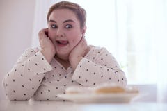 Delighted red-head woman watching her donuts Royalty Free Stock Images Delighted red-head woman watching her donuts Royalty Free Stock Images