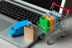 Delivery of orders from the online store. Shopping bags in shopping cart on laptop keyboard and courier delivery truck royalty free stock photos Delivery of orders from the online store. Shopping bags in shopping cart on laptop keyboard and courier delivery truck royalty free stock photos